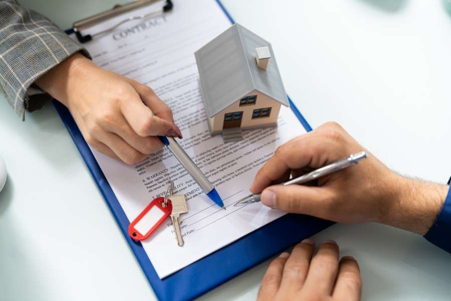 Real estate professional completing rental property tax documentation with contract signing and house model